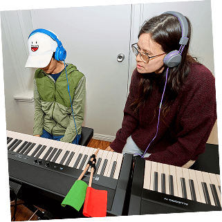 A teacher and a young student review the sheet music together during a piano class.
