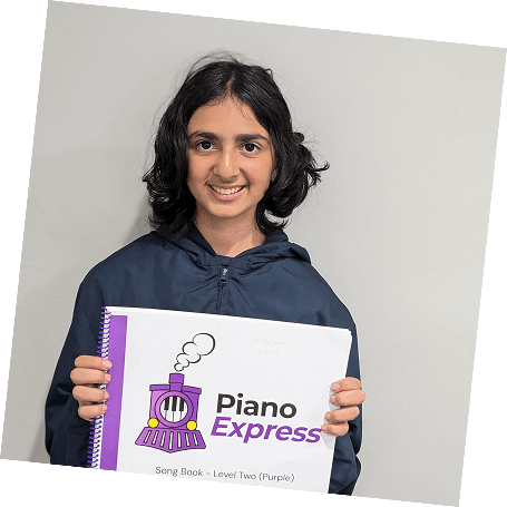 A smiling student proudly holds up her piano book during a piano lesson in Pasadena.