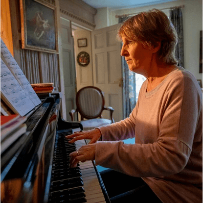 A focused adult woman looks at sheet music while playing the piano in Pasadena.