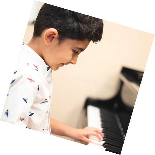 Smiling child playing piano with hands on keys, focused on the instrument at a special needs piano lesson in Pasadena.