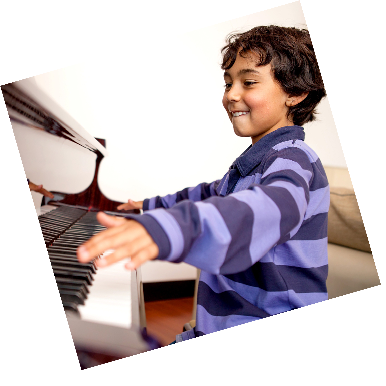 Smiling boy with hands stretched wide, looking at the piano, excited to play.